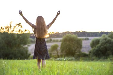 Yeşil çimenlerin tadını çıkaran bir tarlada tek başına duran genç kadın 