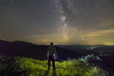 Geceleri dağlarda durup eğlenen bir adamın karanlık silueti