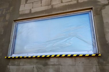 Koruyucu pla ile kaplı inşaat altında bir evin penceresi