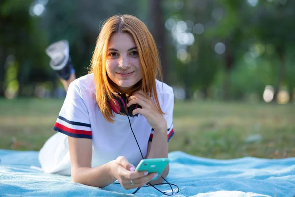 Menina adolescente muito sorridente com cabelo vermelho usando outdoo sellphone — Fotografia de Stock