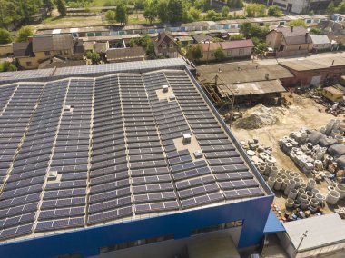 Endüstriyel binaya monte edilmiş birçok güneş panelinin havadan görünümü 