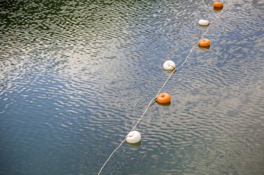 Su yüzeyinde beyaz ve sarı kısıtlama işaretleri olan halat 