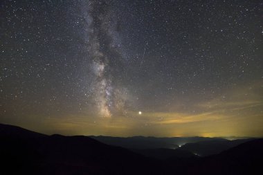 Yıldızların gökyüzüyle kaplı olduğu dağların gece manzarası .