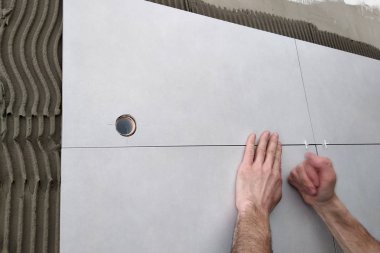 Duvara seramik fayans koyan işçi elleri.
