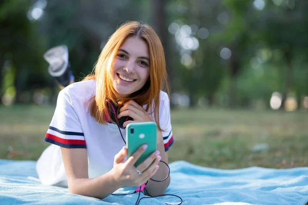 Menina adolescente muito sorridente com cabelo vermelho usando outdoo sellphone — Fotografia de Stock
