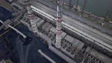 Kömür santralinden gelen gri dumanlı yüksek baca borularının havadan görüntüsü. Fosil yakıtla elektrik üretimi.