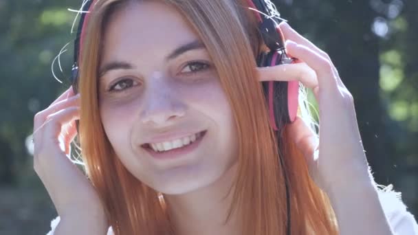 Красивая Девушка Подросток Рыжими Волосами Слушает Музыку Наушниках Открытом Воздухе — стоковое видео