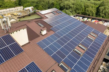 Endüstriyel binaya monte edilmiş birçok güneş panelinin havadan görünümü 