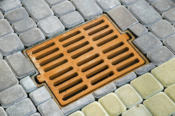 Старая ржавая металлическая канава для дождевой воды на каменной мощеной боковой
