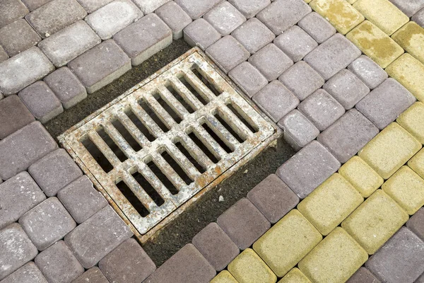 Antiguo canal de metal oxidado para el agua de lluvia en la piedra pavimentada sidewa —  Fotos de Stock