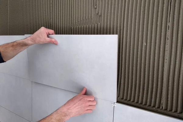 Worker händer sätta keramiska plattor på väggen. — Stockfoto