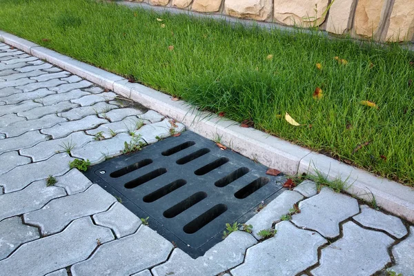 Gouttière de drainage en plastique, pelouse verte et trottoir en pierre sidewa — Photo