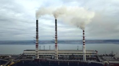 Kömür santralinden gelen gri dumanlı yüksek baca borularının havadan görüntüsü. Fosil yakıtla elektrik üretimi.
