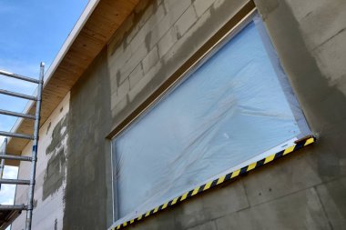 Koruyucu pla ile kaplı inşaat altında bir evin penceresi
