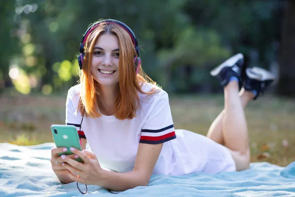Muito sorridente adolescente ouvindo música em fones de ouvido rosa — Fotografia de Stock