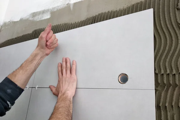 Mains ouvrières mettant des carreaux de céramique sur le mur . — Photo