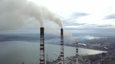 Kömür santralinden gelen gri dumanlı yüksek baca borularının havadan görüntüsü. Fosil yakıtla elektrik üretimi.