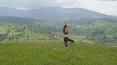 Genç kadın bir yaz günü dağ manzarasının tadını çıkarıyor. Doğa ortamında dinlenme ve meditasyon.