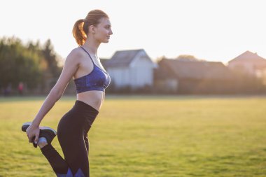 Sabah koşusundan önce spor yapan genç bir kadın.