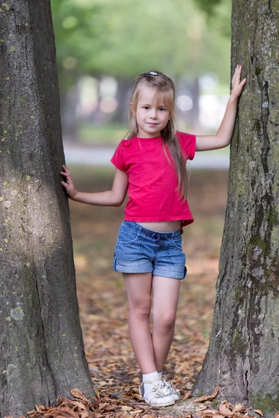 Porträtt av en söt liten flicka som står nära stora träd tr — Stockfoto