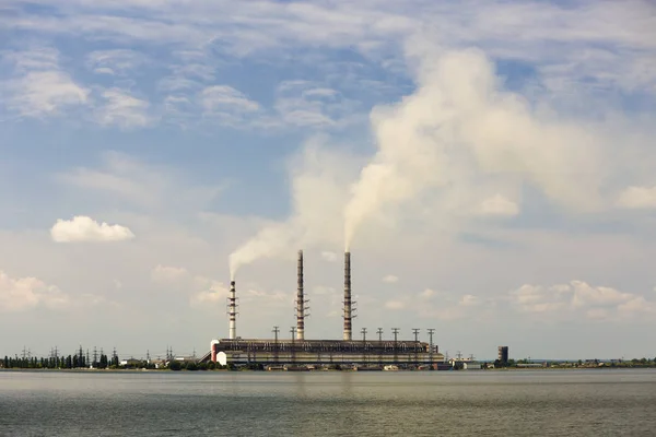 Thermal power station tall pipes with thick smoke reflected in l