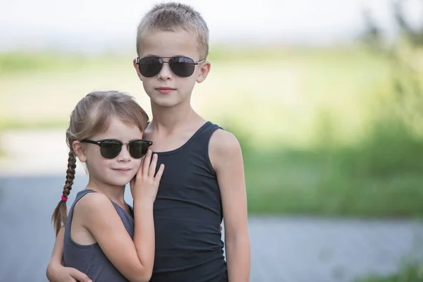 Dwoje dzieci w czarnych okularach przeciwsłonecznych bawiących się na świeżym powietrzu — Zdjęcie stockowe