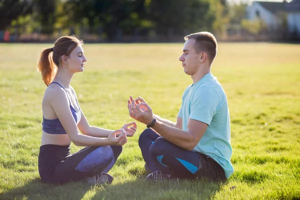 Young couple having fun outdoors. Man and woman meditating toget — Stock Photo, Image