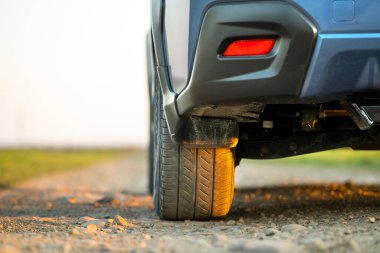 Çakıl yolundaki mavi off-road araba tekerleğini kapatın. Otomobille seyahat, vahşi yaşam macerası, keşif gezisi ya da bir SUV otomobili ile aşırı seyahat. Offroad 4x4 aracı gün doğumunda arazide olacak..