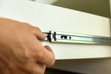 Marangoz ellerinin çağdaş dolaba kayan kızakların üzerine ahşap çekmece kurmasını kapat..