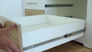 Erkek marangoz ellerinin mobilya dolabını monte etmesi ve yeni ahşap çekmece takması..