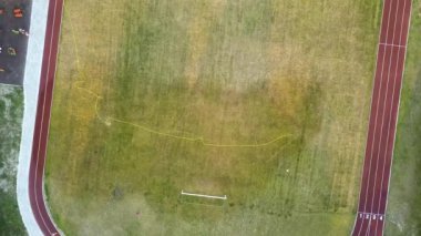 Yeşil çimenler ve su püskürten fıskiyelerle kaplı futbol sahası yüzeyinin yukarıdan görünüşü.