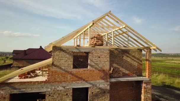 木造屋根枠構造の未完成のレンガ造りの家の空中ビュー建設中 — ストック動画