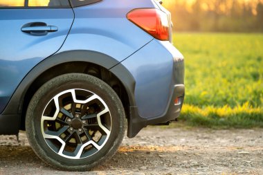 Çakıl yolundaki mavi off-road araba tekerleğini kapatın. Otomobille seyahat, vahşi yaşam macerası, keşif gezisi ya da bir SUV otomobili ile aşırı seyahat. Offroad 4x4 aracı gün doğumunda arazide olacak..