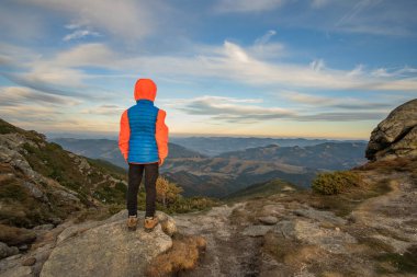 Genç çocuk yürüyüşçü dağlarda duruyor ve muhteşem dağ manzarasının tadını çıkarıyor..