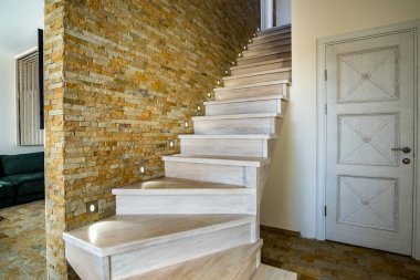 Stylish wooden contemporary staircase inside loft house interior. Modern hallway with decorative limestone brick walls and white oak stairs. clipart