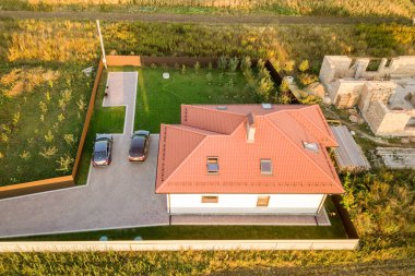 İki özel evin yukarıdan aşağı görüntüsü, biri beton temeli ve tuğla duvarlı, diğeri de kırmızı kiremitli çatıyla bitirilmiş..