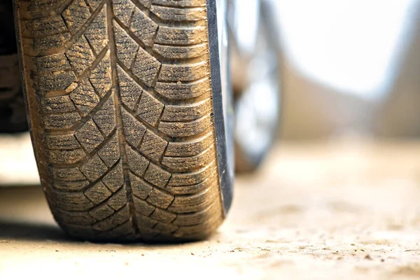 Close up of dirty car wheel with rubber tire covered with yellow mud.