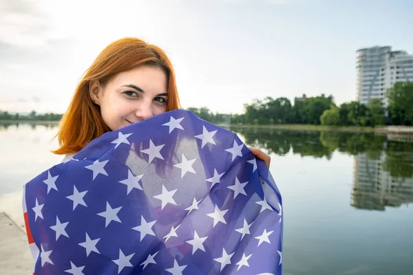 Szczęśliwa Młoda Ruda Kobieta Flagą Usa Ramionach Stojąca Świeżym Powietrzu — Zdjęcie stockowe