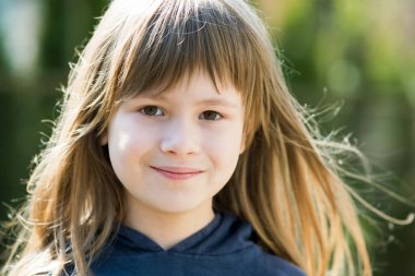 Gri gözlü ve açık havada gülümseyen uzun sarı saçlı güzel bir kız çocuğu portresi. Sıcak yaz gününde tatlı bir bayan çocuk..