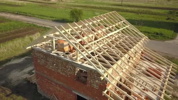 木造屋根枠構造の未完成のレンガ造りの家の空中ビュー建設中 — ストック動画