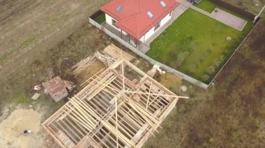 Biri ahşap çatı iskeleti ve diğeri de kırmızı kiremit çatılı iki özel evin yukarıdan aşağıya bakan görüntüsü..