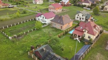 Banliyö evleri ve yeşil çimlerle kaplı özel ev çatıda güneş panelleri, mavi su ve rüzgar türbini jeneratörlü yüzme havuzu..