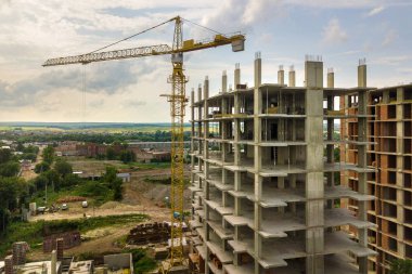 Kule görüntüsü, vinç kaldırma ve inşaat halindeki uzun apartmanın beton iskeleti. Kentsel kalkınma ve gayrimenkul büyüme kavramı.