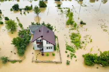 Aerial view of flooded house with dirty water all around it. clipart