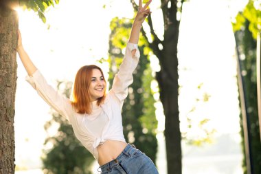 Gündelik kıyafetler giyen mutlu genç kadın yaz parkında sıcak bir günün tadını çıkarıyor. .