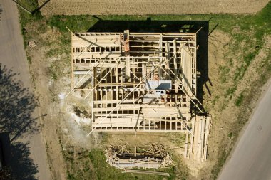 İnşaat halindeki ahşap çatı iskeleti olan bitmemiş tuğla evin havadan görüntüsü..