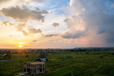 Turuncu batan güneş ve mavi gökyüzü tarafından aydınlatılan kabarık bulutlarla dramatik günbatımı kırsal manzarası.