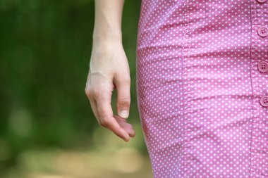 Kadın eli ve pembe elbisesi yakın çekim.