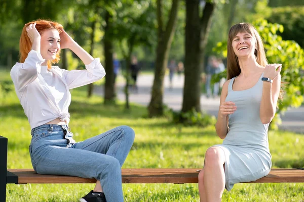 Dos Jóvenes Amigas Sentadas Banco Parque Verano Charlando Felizmente Divirtiéndose —  Fotos de Stock