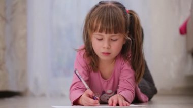 Güzel kız bir odada yere bir kağıt parçası yazıyor..